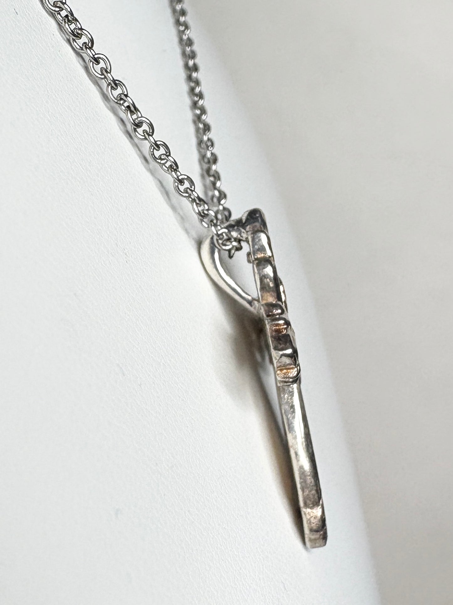 Ornate Black Hills Gold cross pendant with green and rose gold leaves on a yellow gold base.