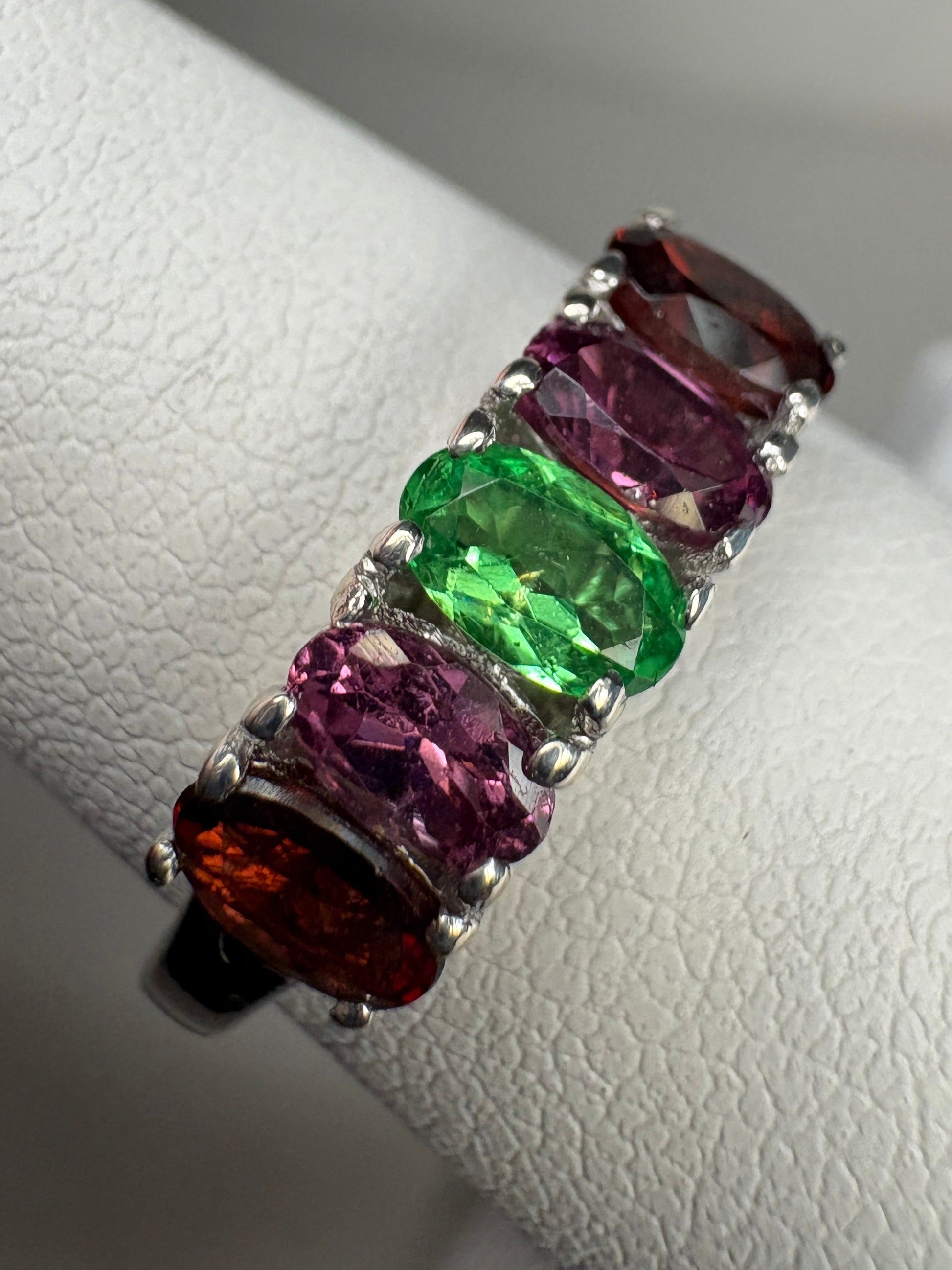Sterling silver ring with five oval garnets in shades of red, pink, and green.