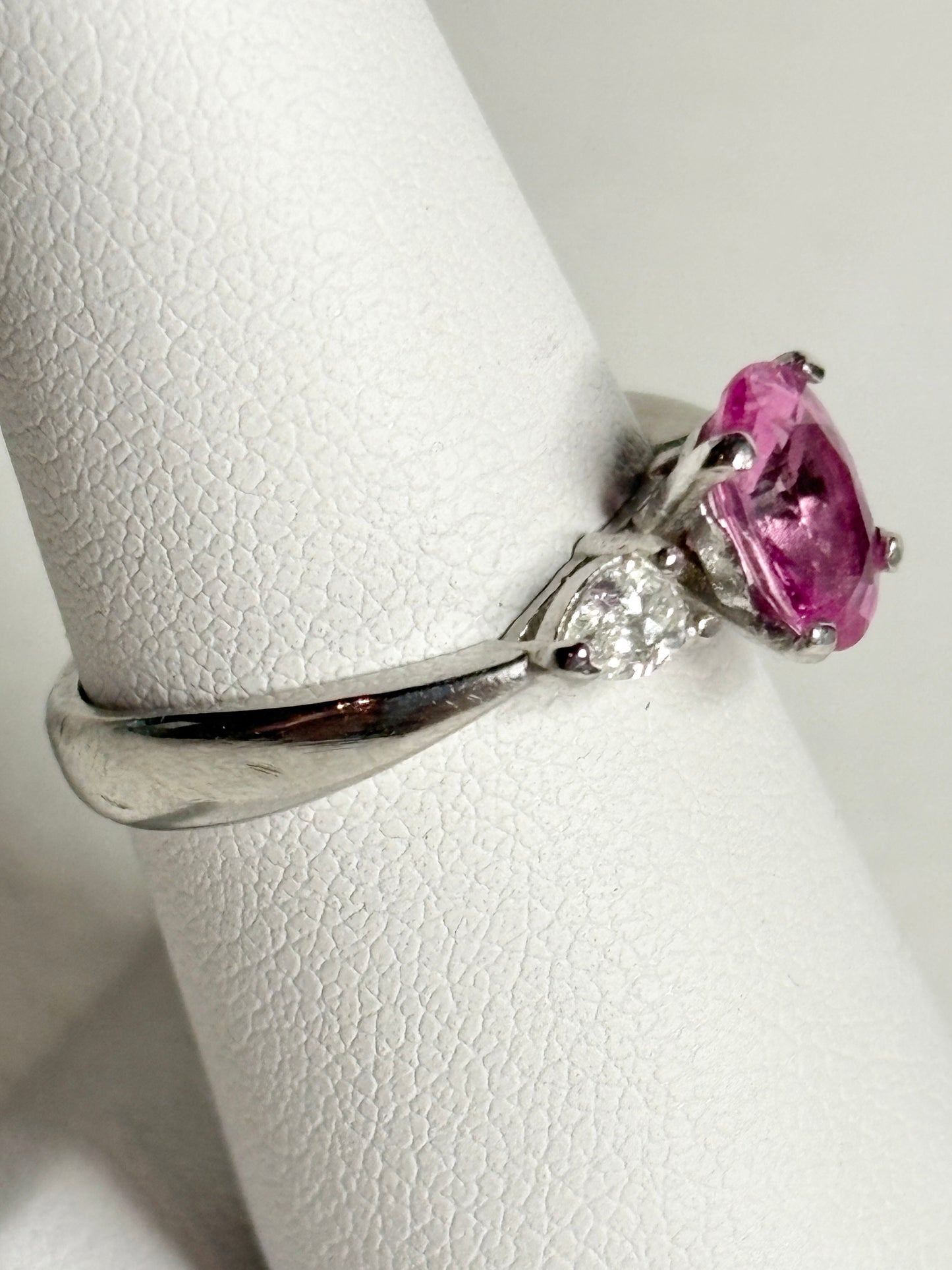 Platinum ring with a pink sapphire and two pear-shaped diamonds.