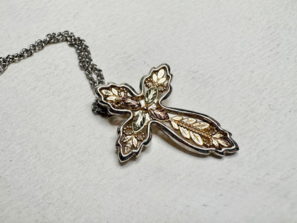 Black Hills Gold ornate cross pendant with sterling silver frame and stainless steel chain.