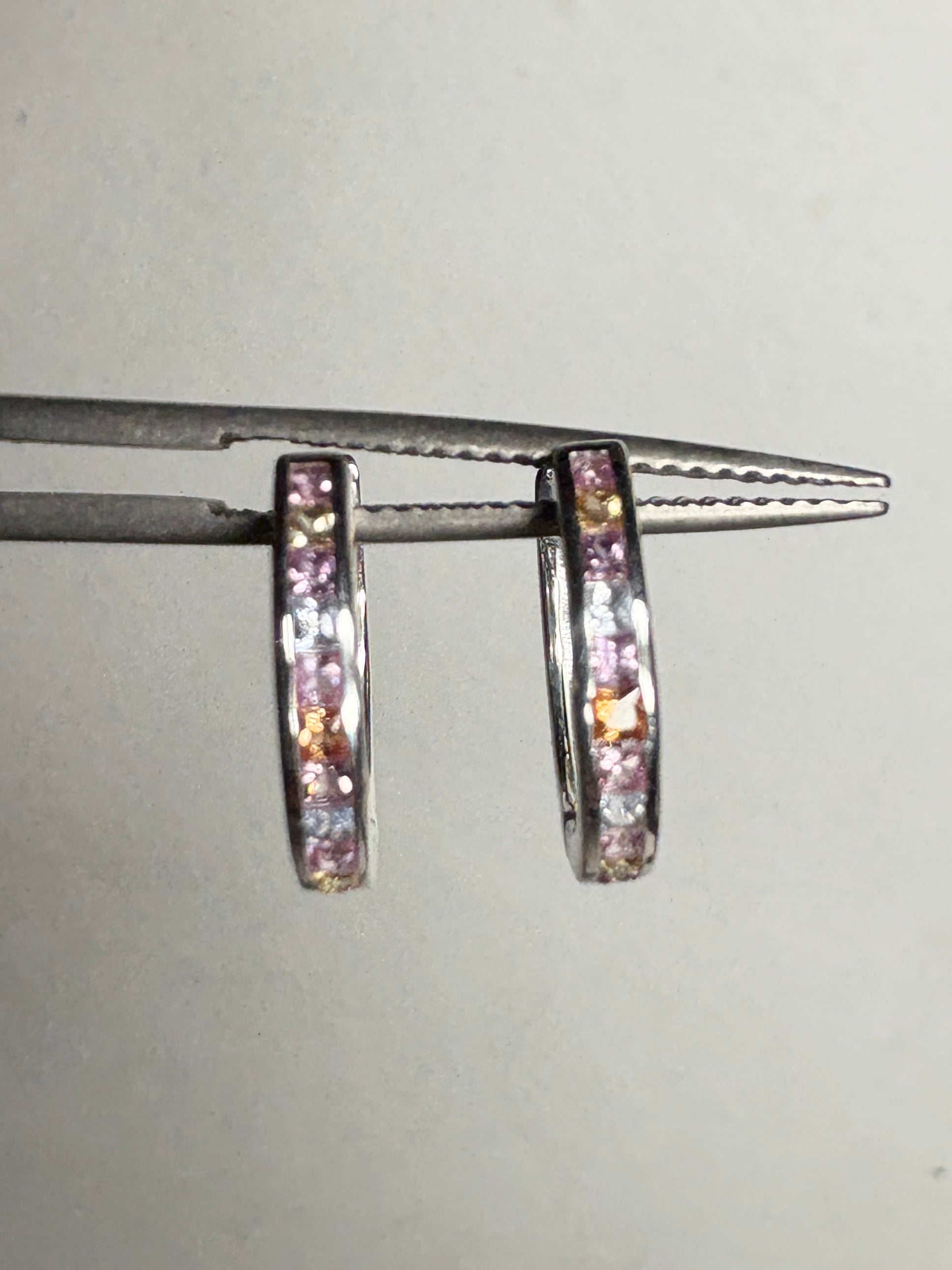 Sterling silver huggie hoop earrings with princess-cut multi-color sapphires.