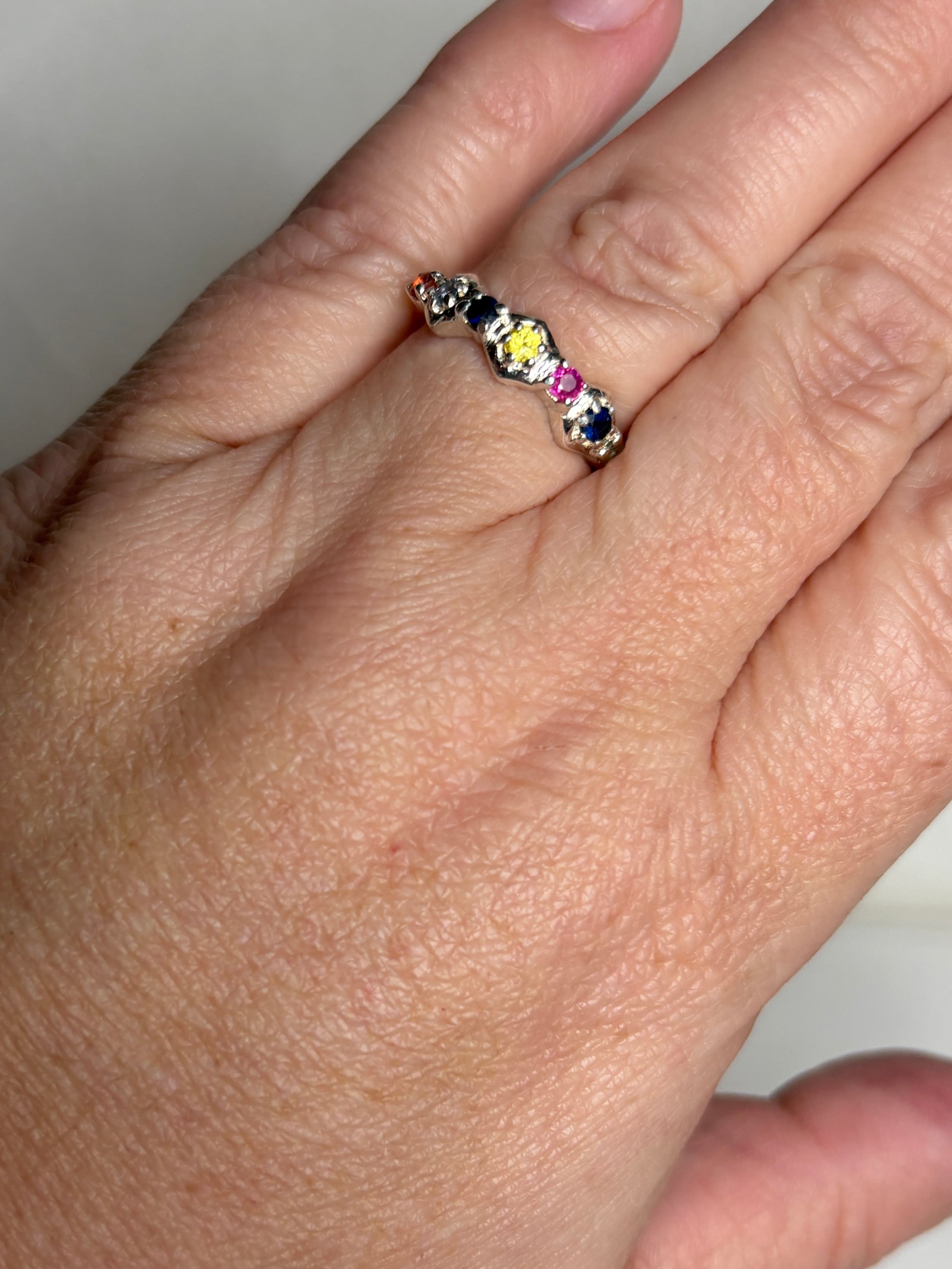 Sterling silver band ring with honeycomb shapes and multi-colored sapphires and ruby.