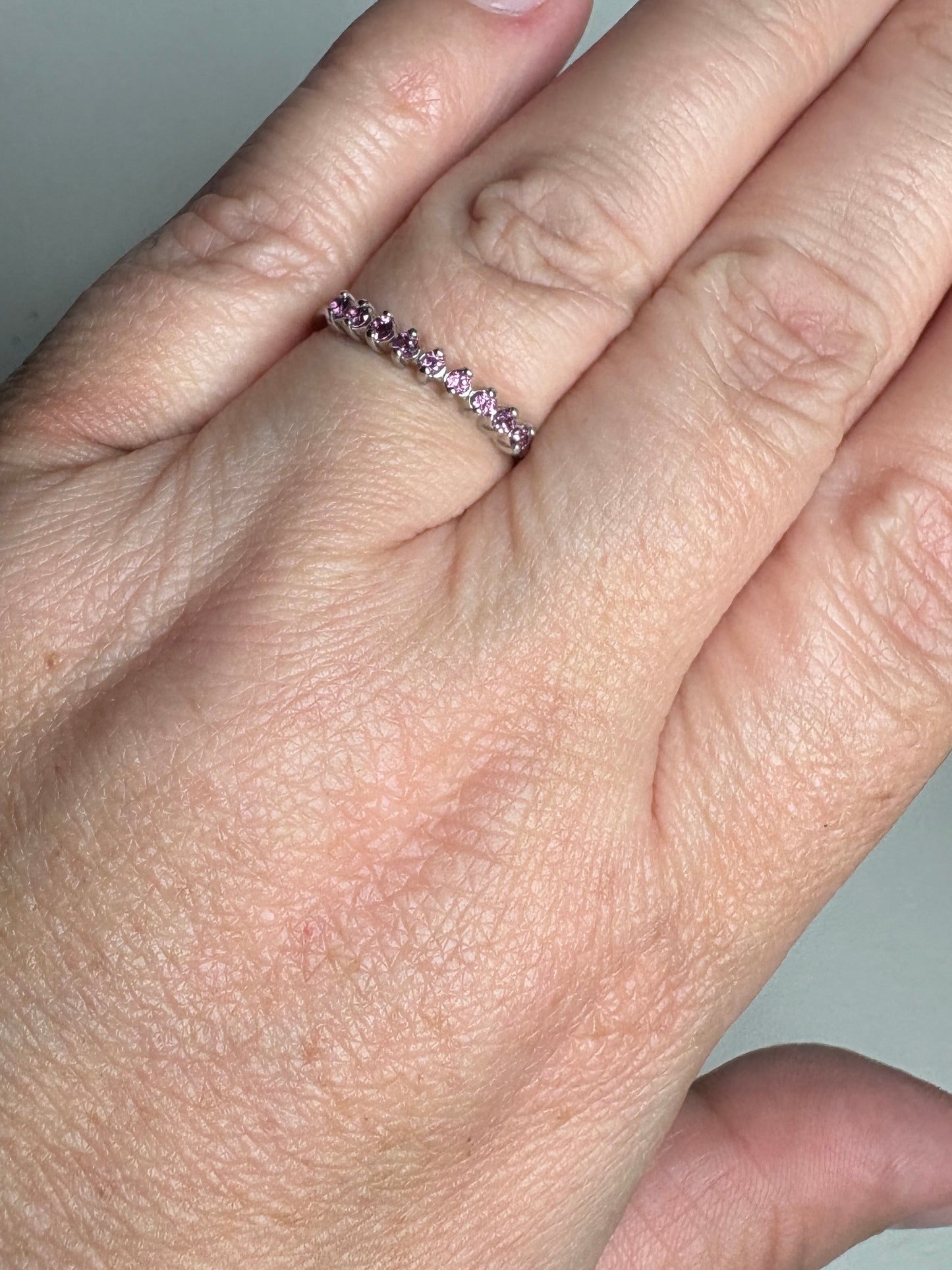 Sterling silver band ring with small pink rhodolite garnets.