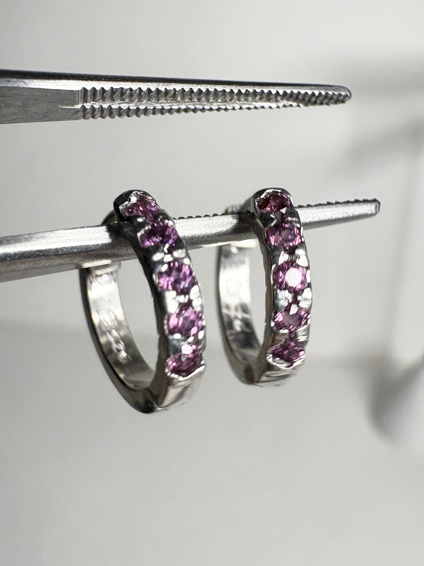 Small sterling silver huggie hoop earrings with rhodolite garnets.