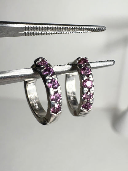 Small sterling silver huggie hoop earrings with rhodolite garnets.