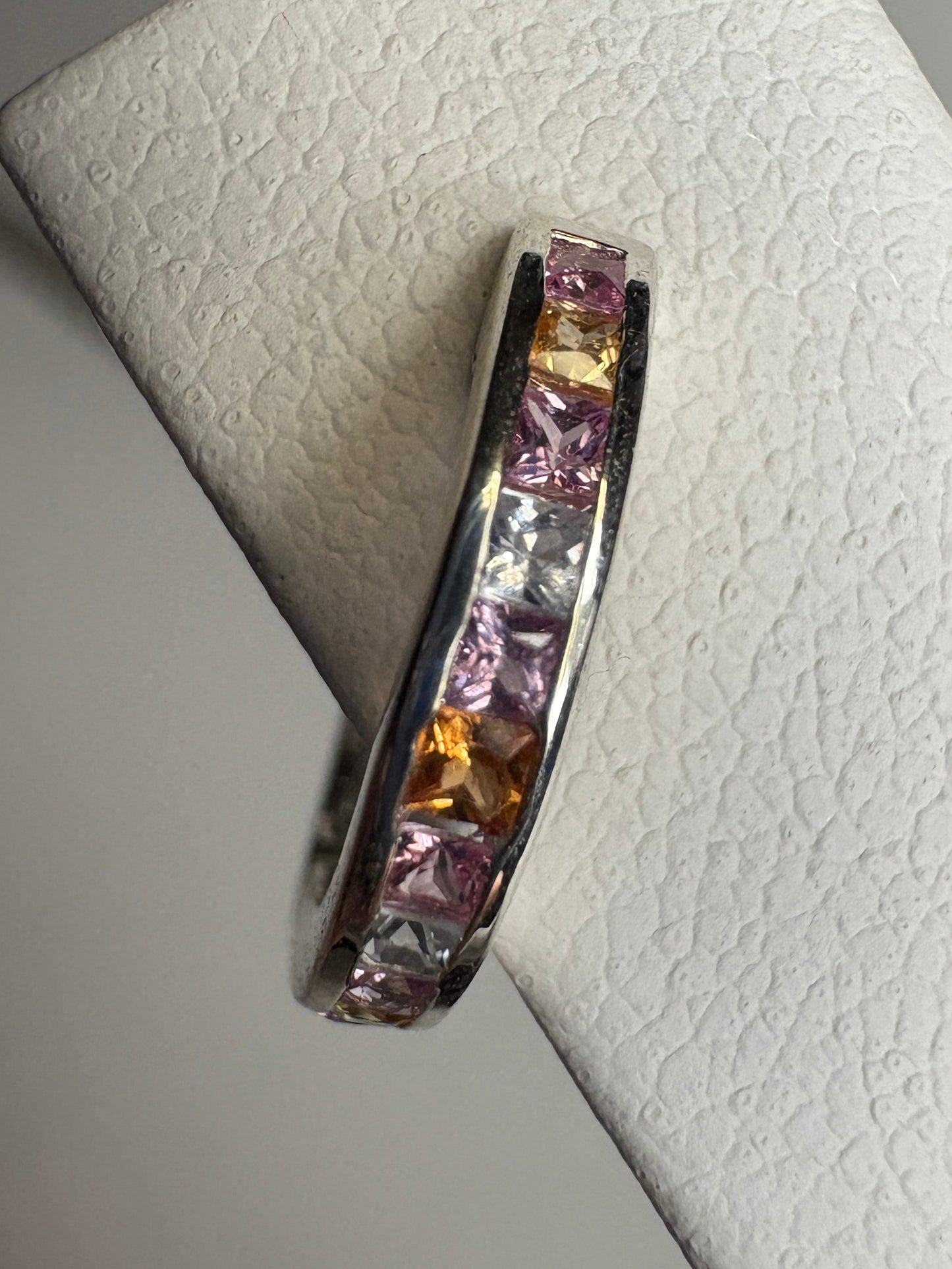 Sterling silver huggie hoop earrings with channel-set multi-color princess-cut sapphires.