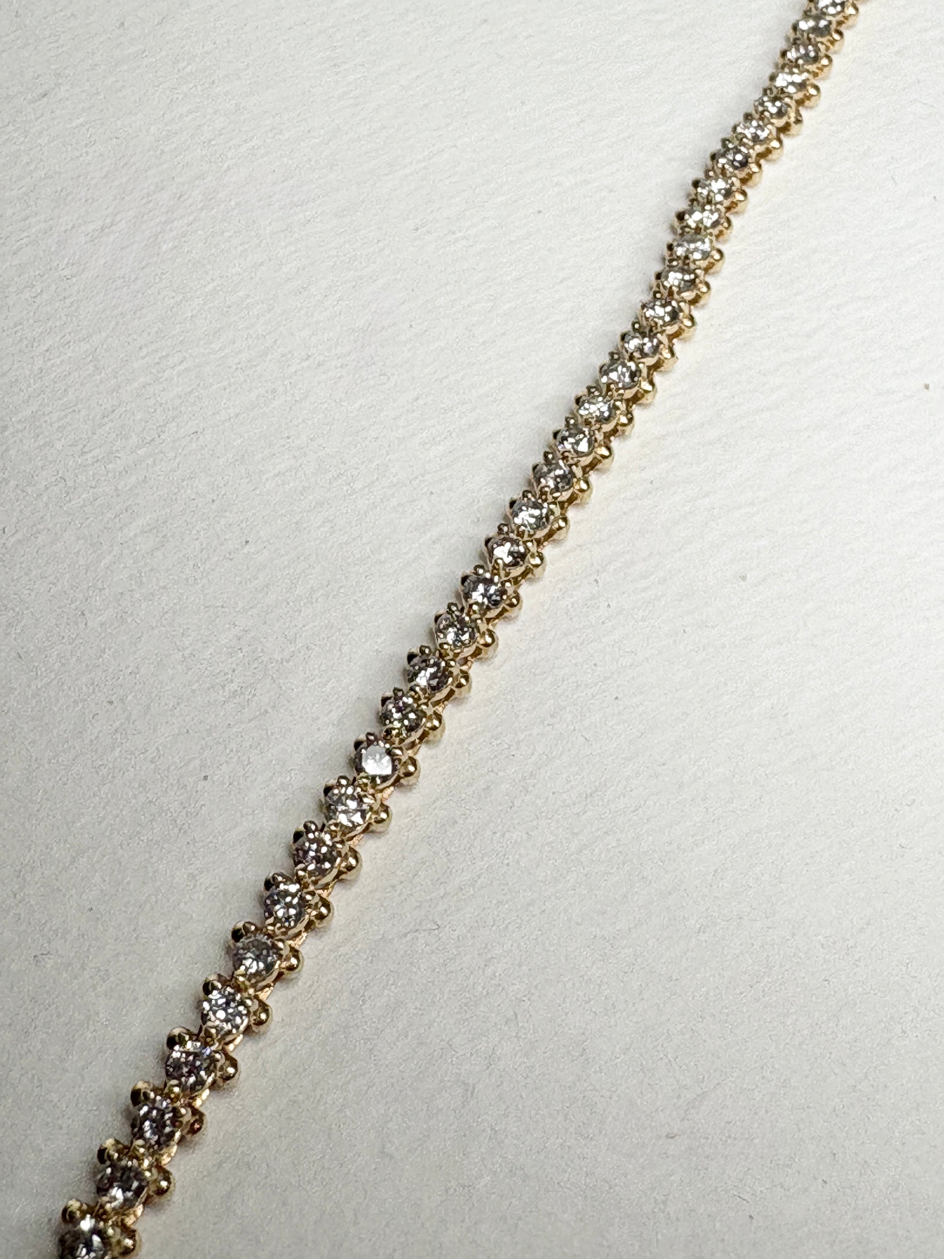 A 14k gold tennis bracelet with 57 round diamonds.