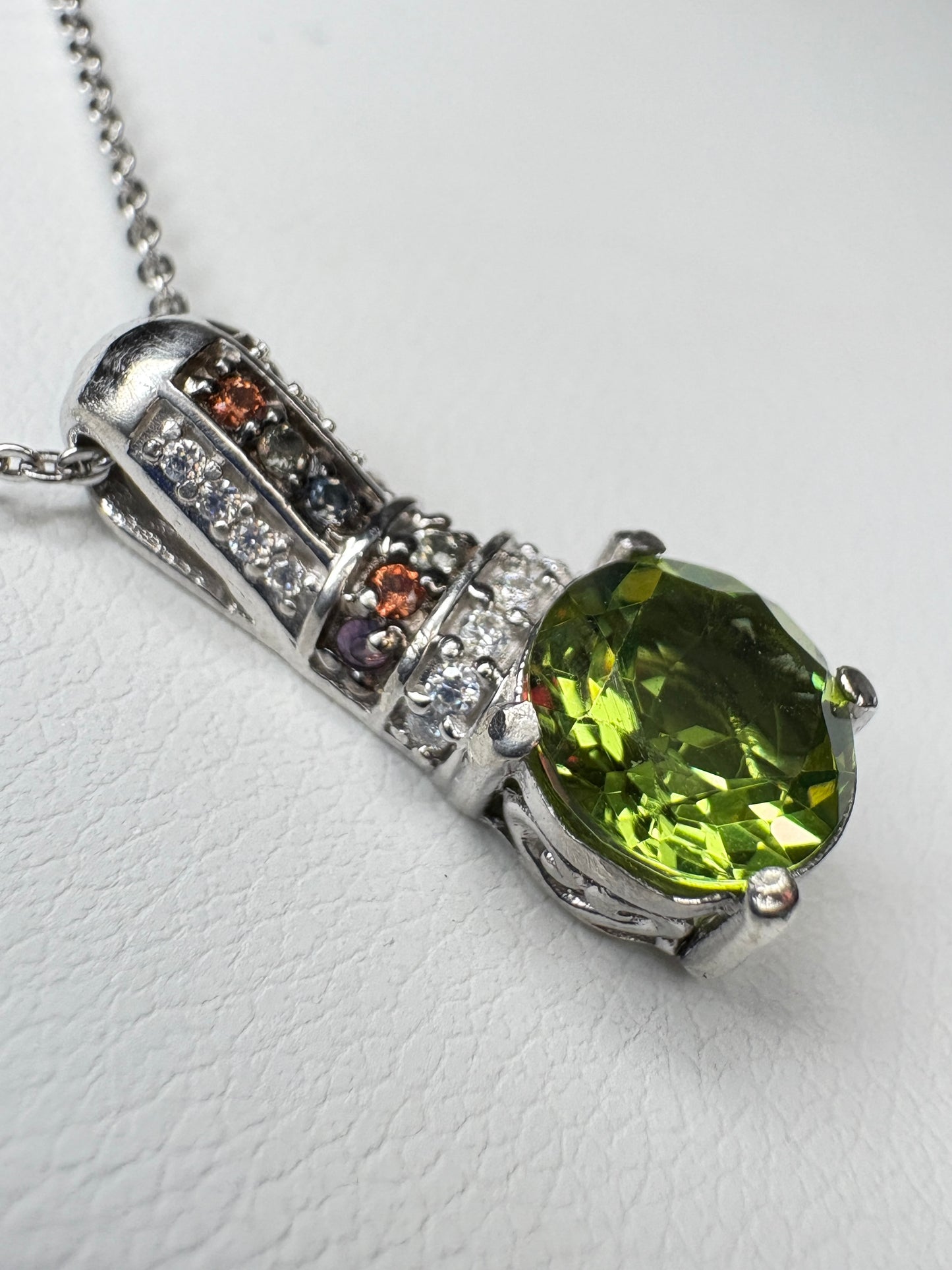 Sterling silver pendant necklace with a color-changing glass stone, moissanite, and multi-colored sapphires.