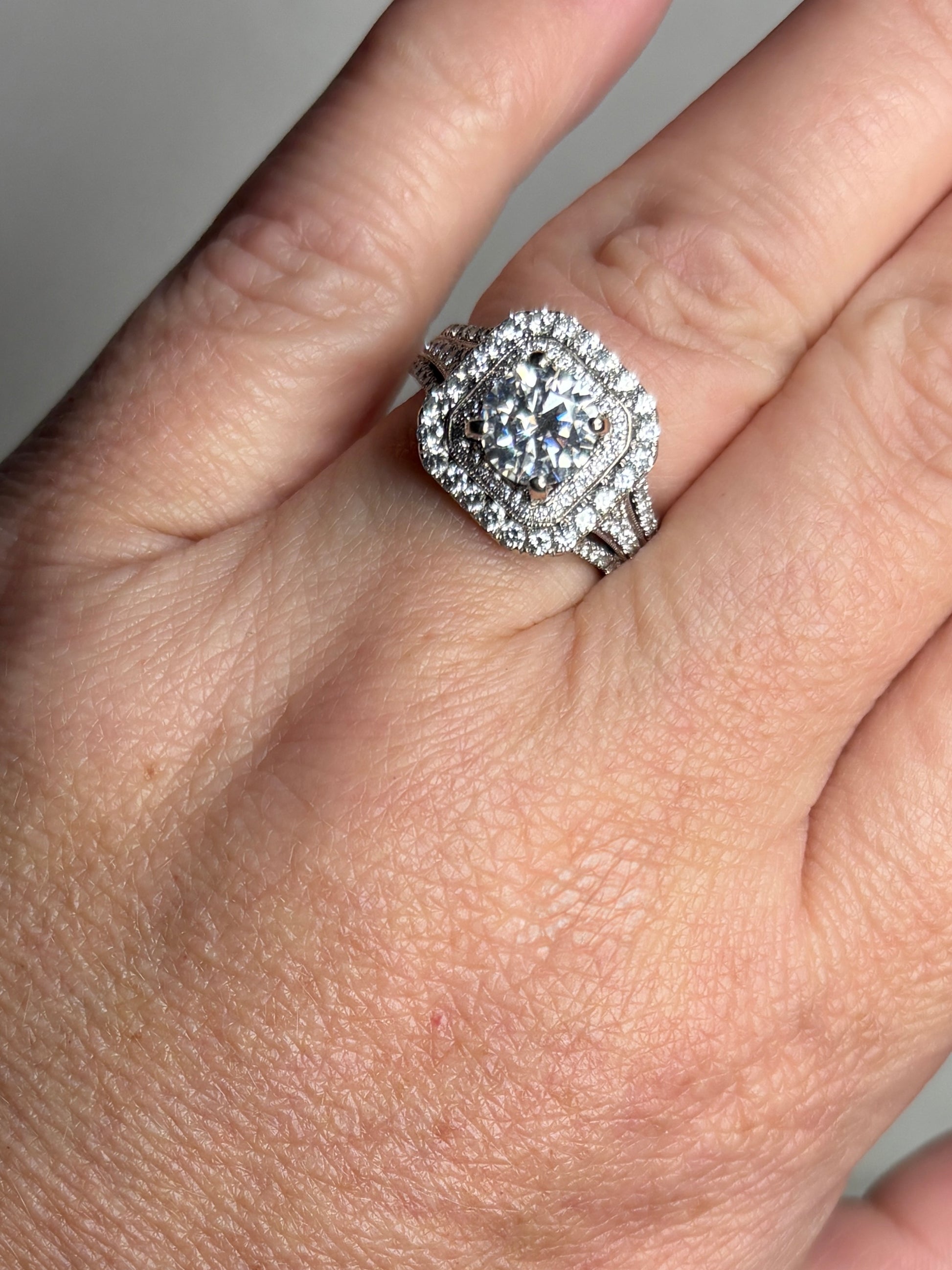 A 14k white gold ring with a large center stone and a double halo of diamonds.