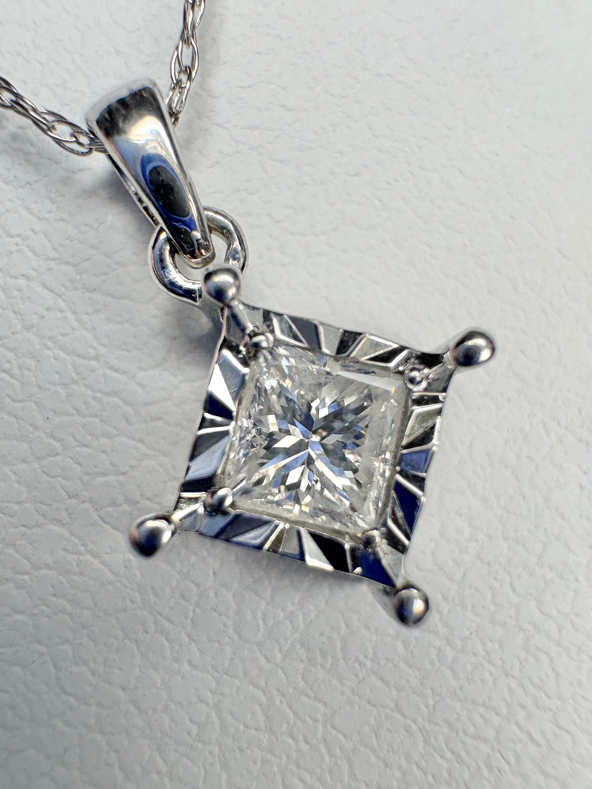 A princess cut diamond pendant necklace on a 21" white gold rope chain.