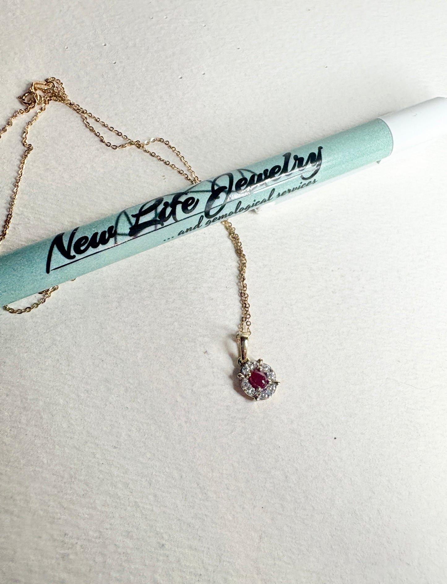 A gold necklace with a ruby and diamond pendant.