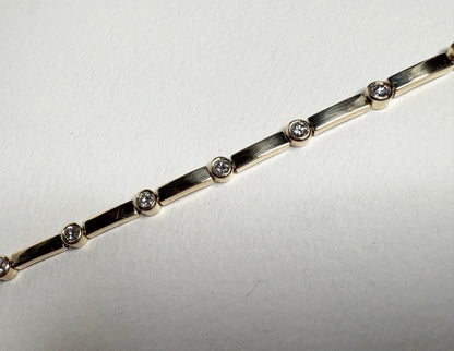 A 14k yellow gold tennis bracelet with 11 bezel-set diamonds.
