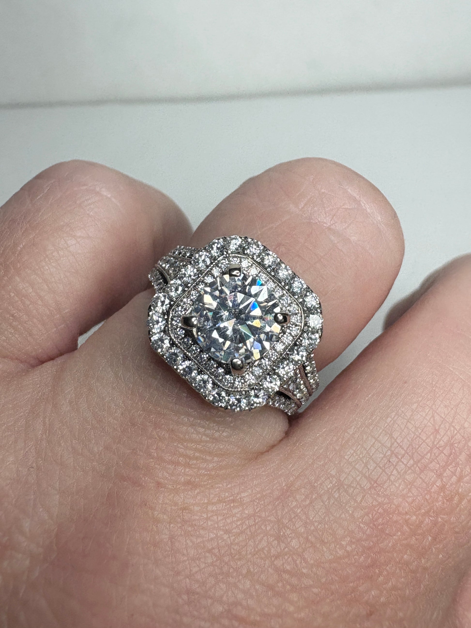 A 14k white gold ring with a large center stone and a double halo of natural diamonds.