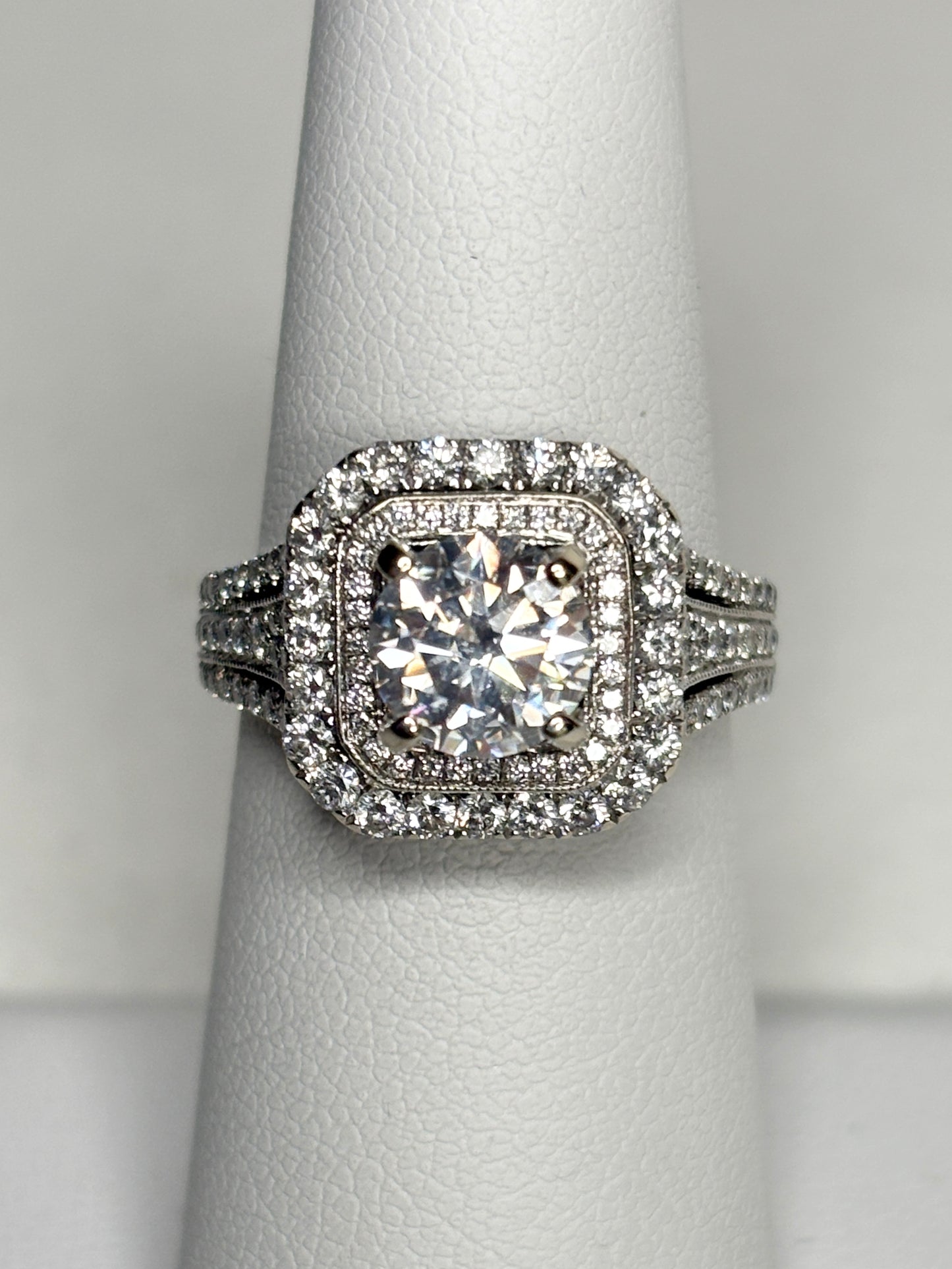 A 14k white gold ring with a central moissanite and a double halo of natural diamonds.