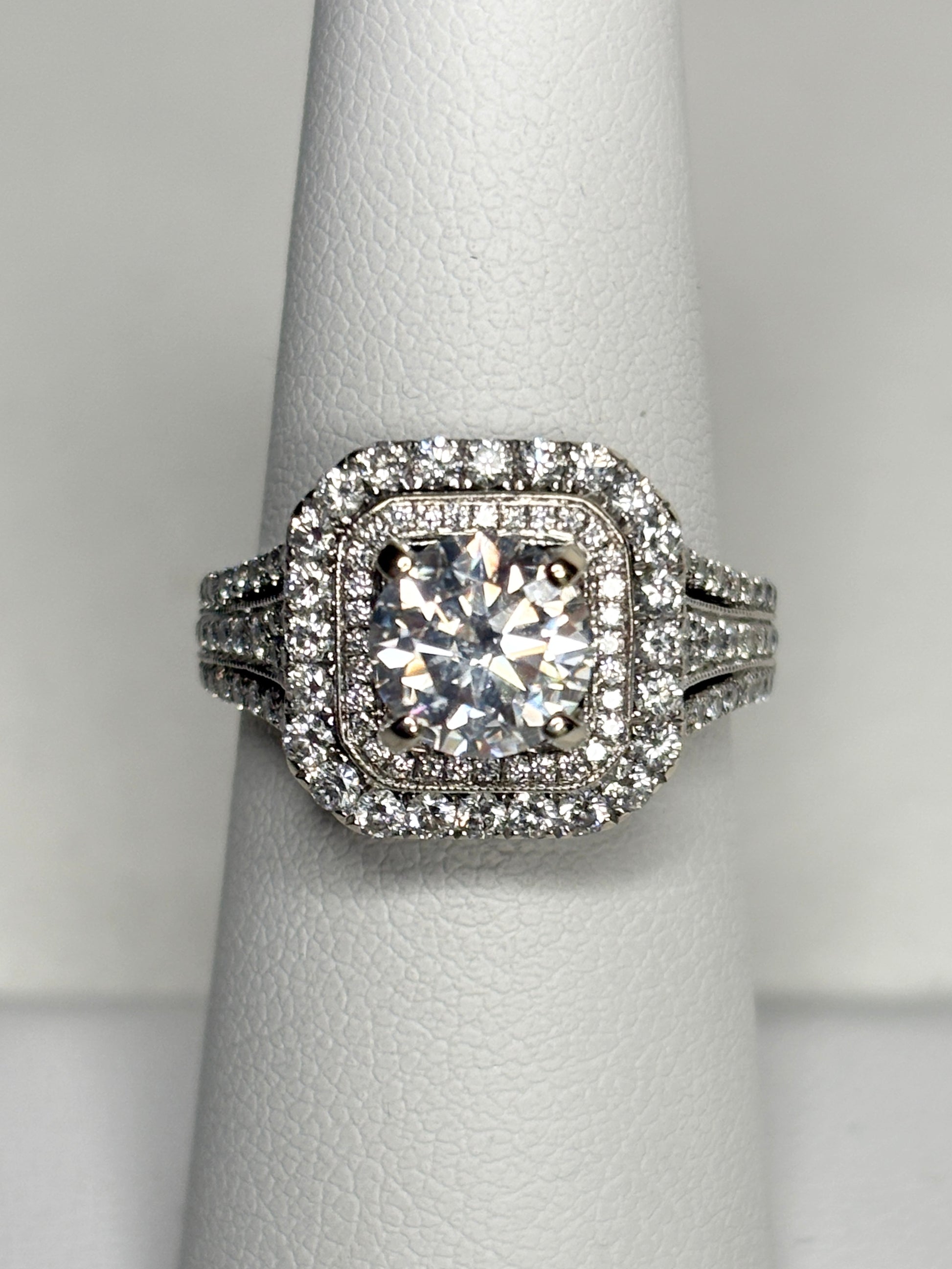 A 14k white gold ring with a central moissanite and a double halo of natural diamonds.