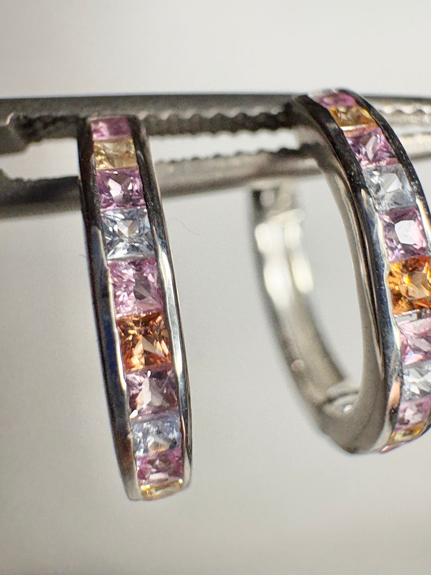 Sterling silver huggie hoop earrings with princess-cut multi-color sapphires.