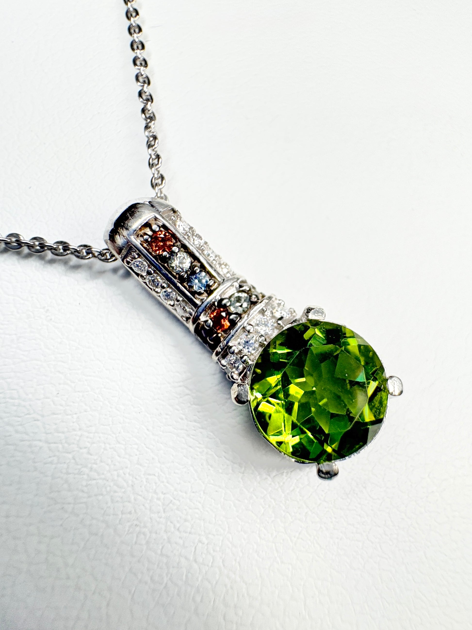 Sterling silver pendant necklace with a green color-change glass stone and multi-colored sapphires.