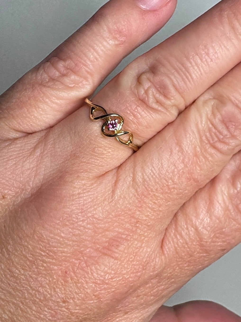 A 10k gold ribbon style ring with a pink bixbite gemstone.
