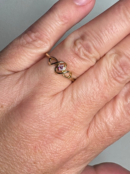A 10k gold ribbon style ring with a pink bixbite gemstone.