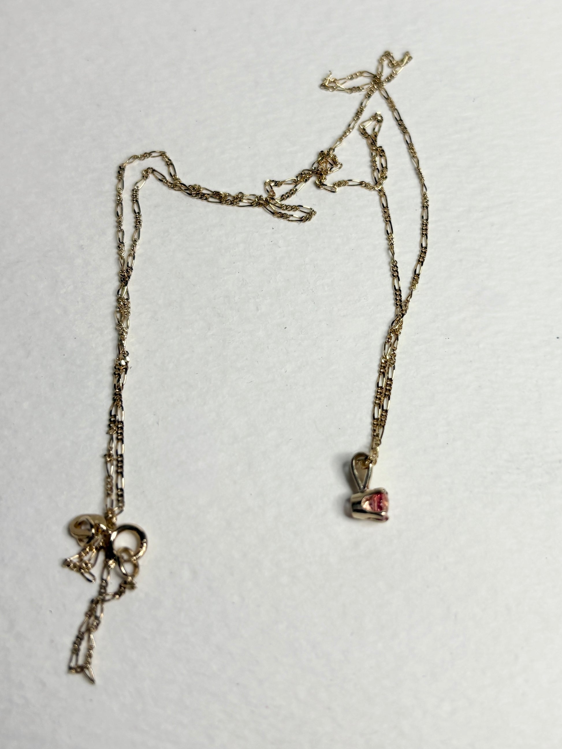 Small 14k gold necklace with a pink sapphire pendant and figaro chain.