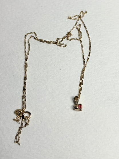 Small 14k gold necklace with a pink sapphire pendant and figaro chain.