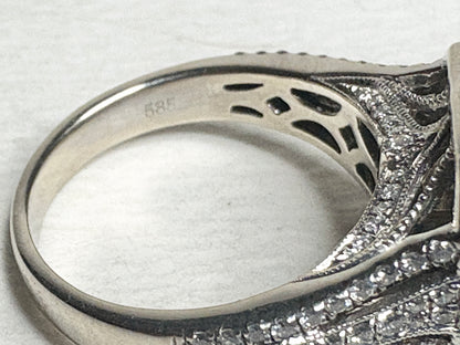 A 14k white gold ring with "585" stamped inside, featuring intricate detailing and small diamonds.