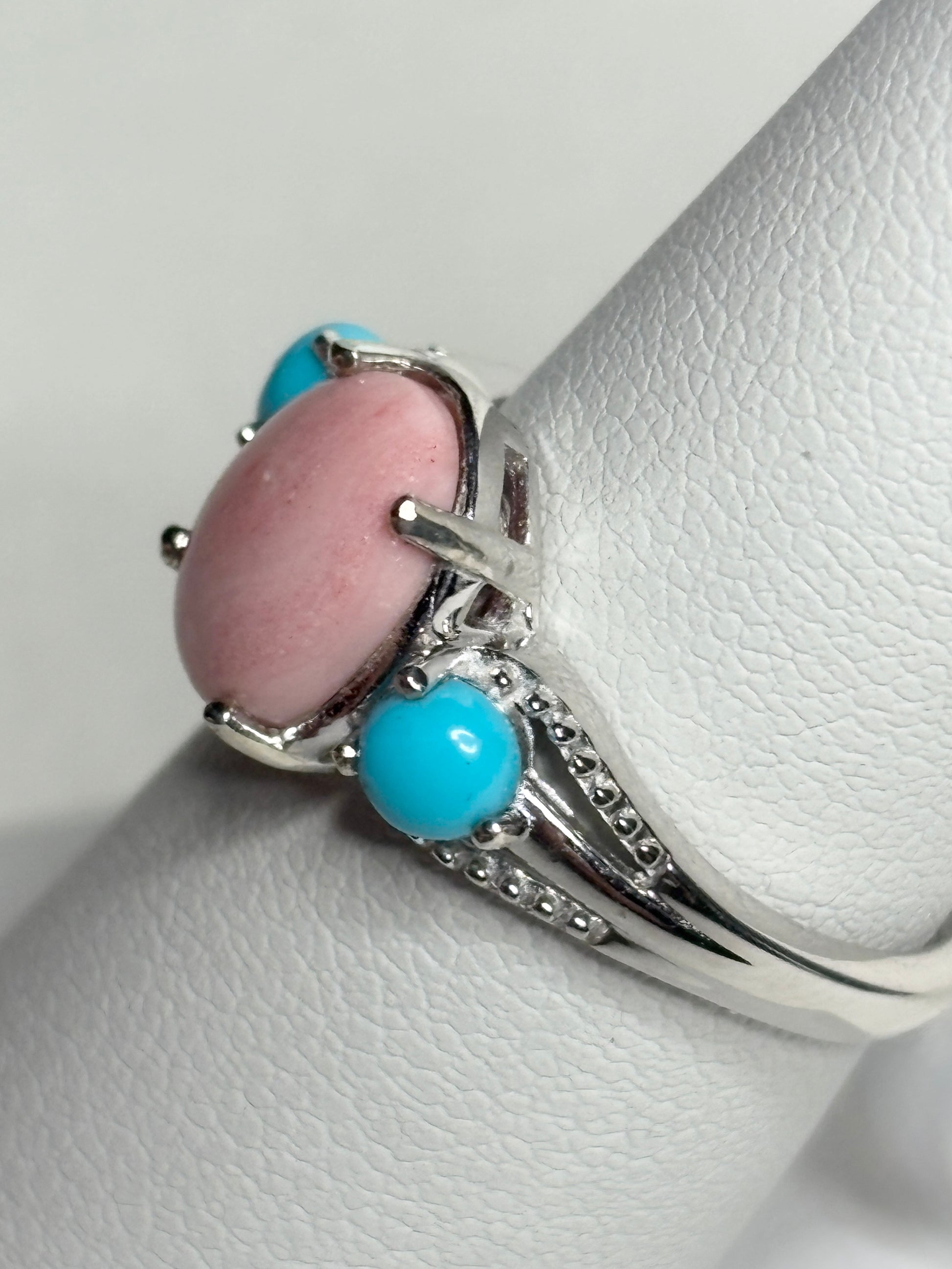 Sterling silver ring with oval peach opal and round turquoise cabochons.