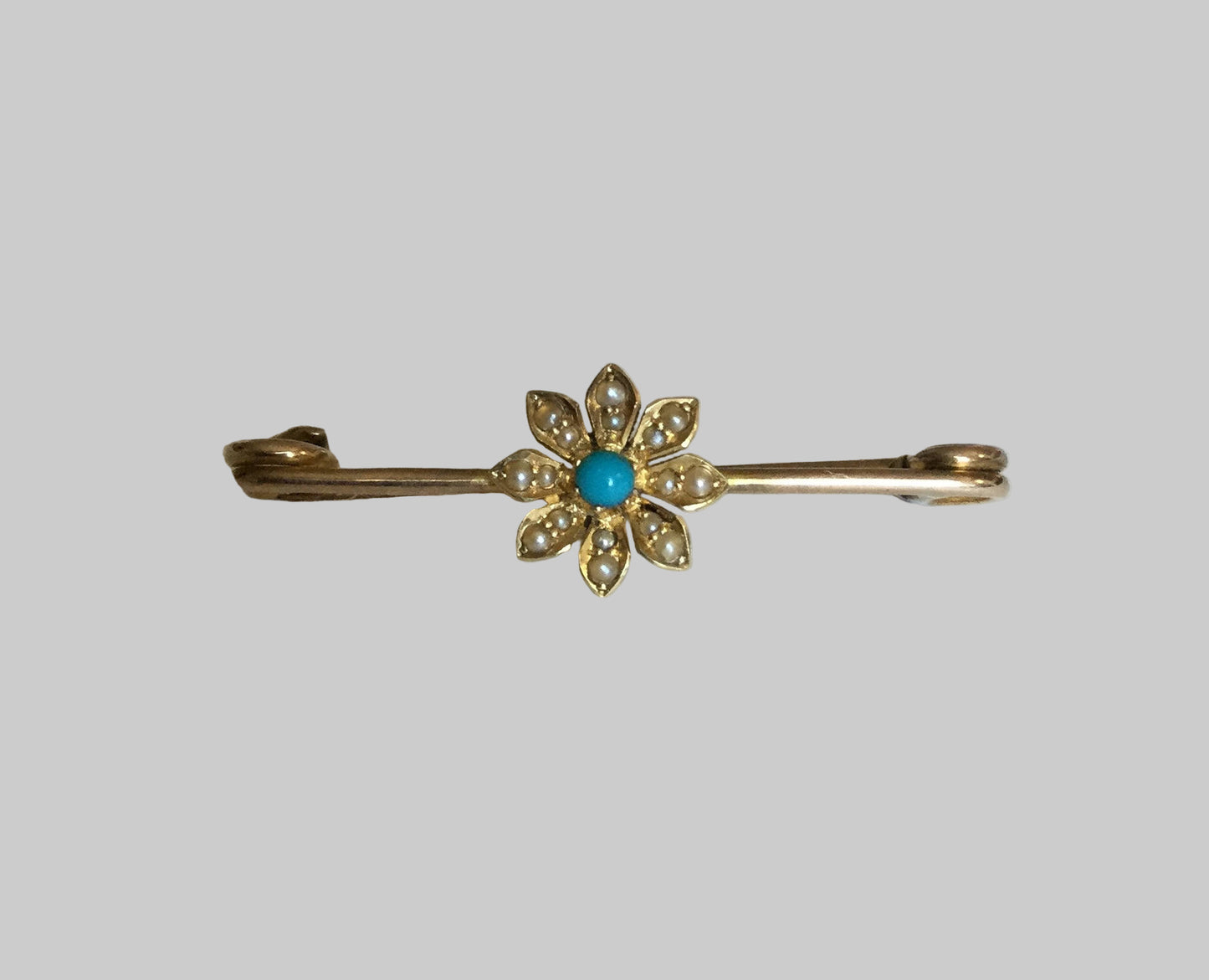 Gold bar pin with a turquoise and seed pearl daisy.