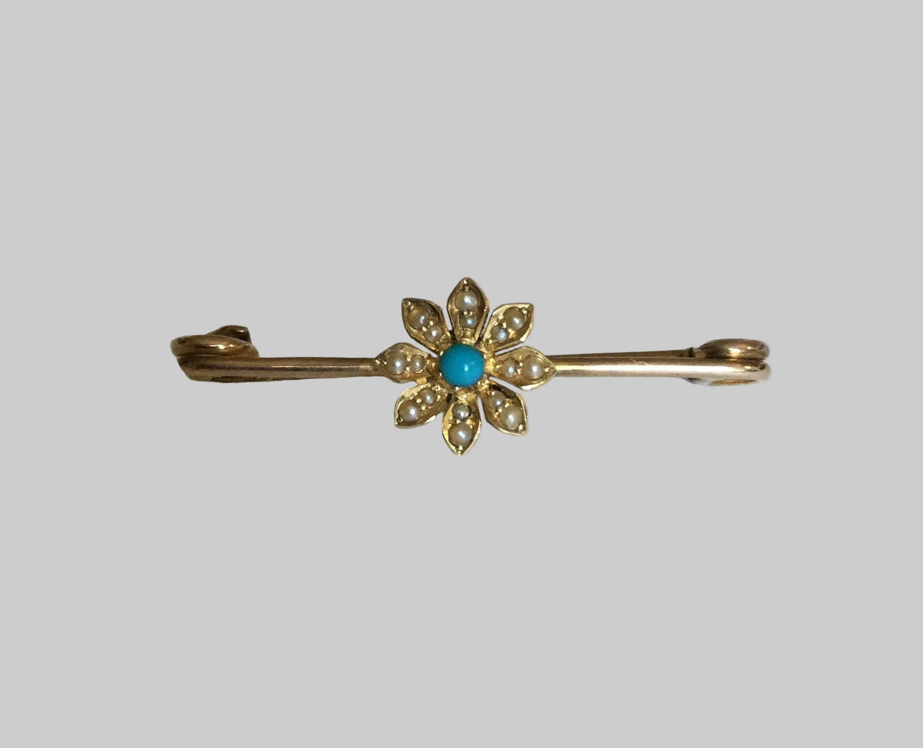Gold bar pin with a turquoise and seed pearl daisy.