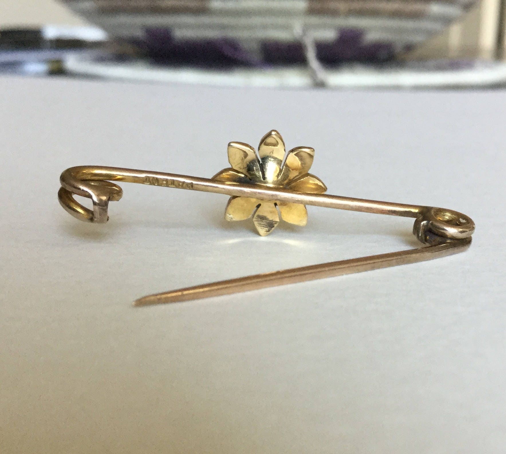 Gold pin with a flower design featuring a turquoise and seed pearls.