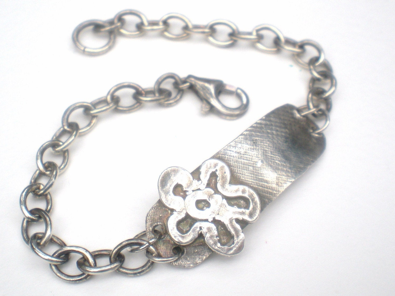 Sterling silver bracelet with a rugged ID tag and flower charm.