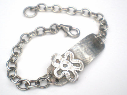 Sterling silver bracelet with a rugged ID tag and flower charm.