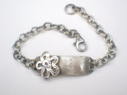 Sterling silver bracelet with a flower charm and rugged ID tag.
