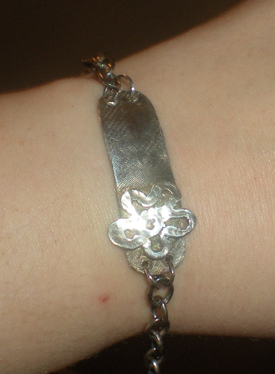 Sterling silver bracelet with a rugged ID tag and flower charm.