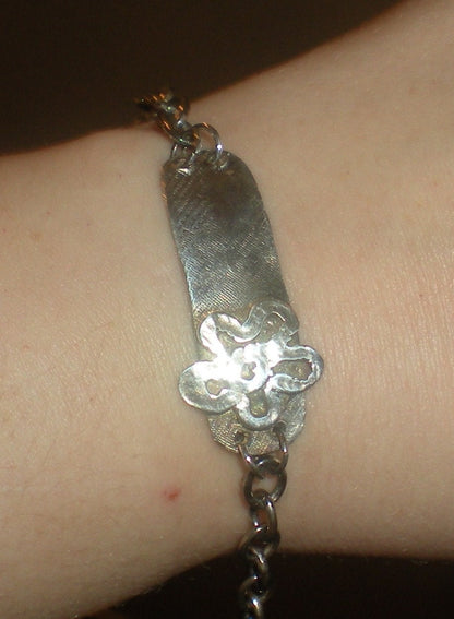 Sterling silver bracelet with a rugged ID tag and flower charm.