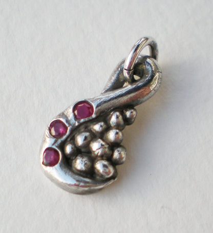 Fine solid silver pendant with a swirl design, pebbles, and three natural rubies.