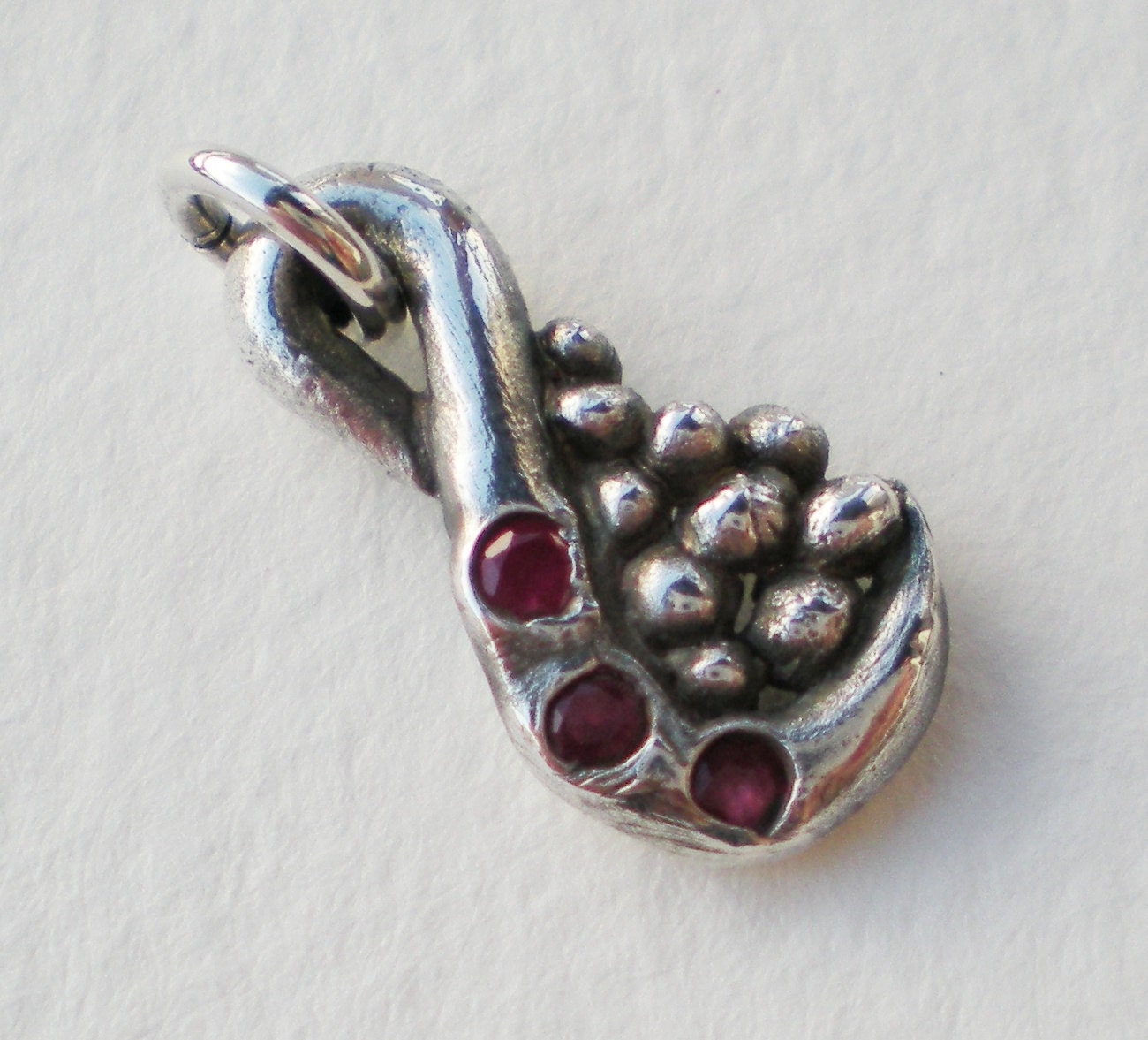 Fine solid silver pendant with a swirl design, pebbles, and three natural rubies.