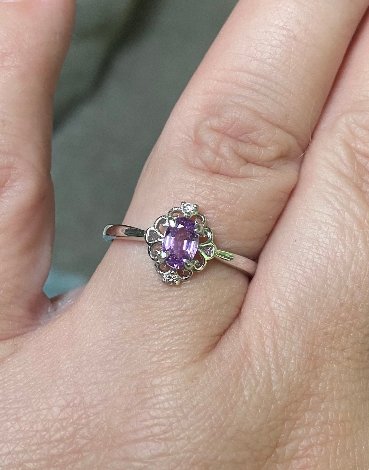 Sterling silver ring with oval pinkish-purple sapphire and diamond accents.