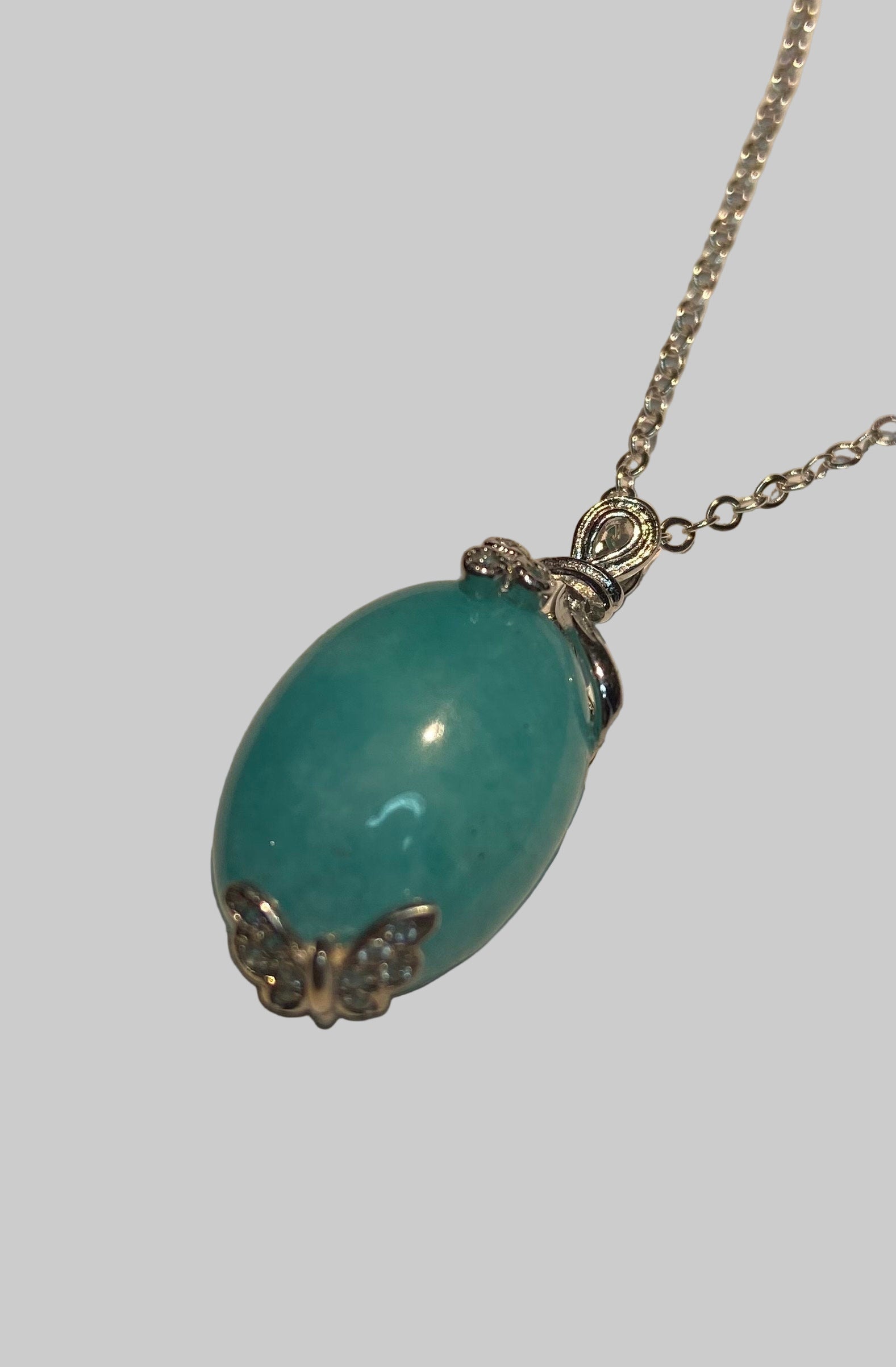 Sterling silver necklace with a Peruvian amazonite pendant featuring butterfly and floral ribbon details.