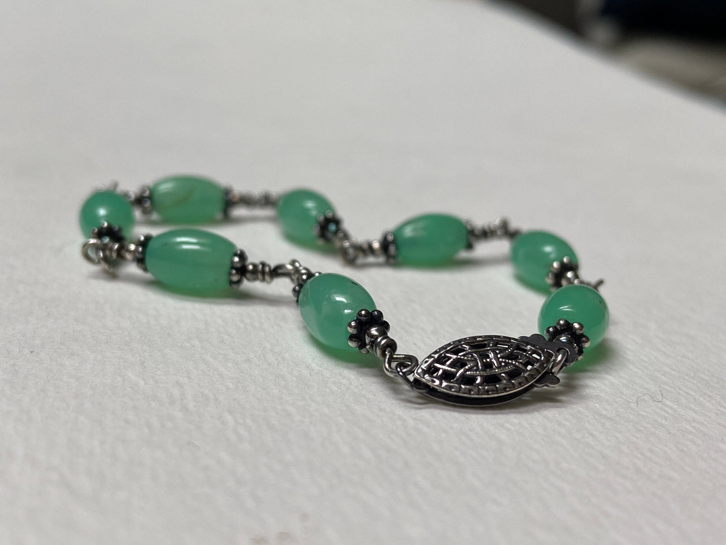 Sterling silver wire bracelet with oval chrysoprase beads and a filigree clasp.