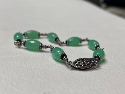 Sterling silver wire bracelet with oval chrysoprase beads and a filigree clasp.