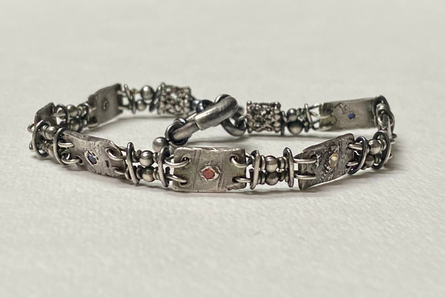 Hand forged sterling silver bracelet with multi-colored sapphires and PMC silver stations.