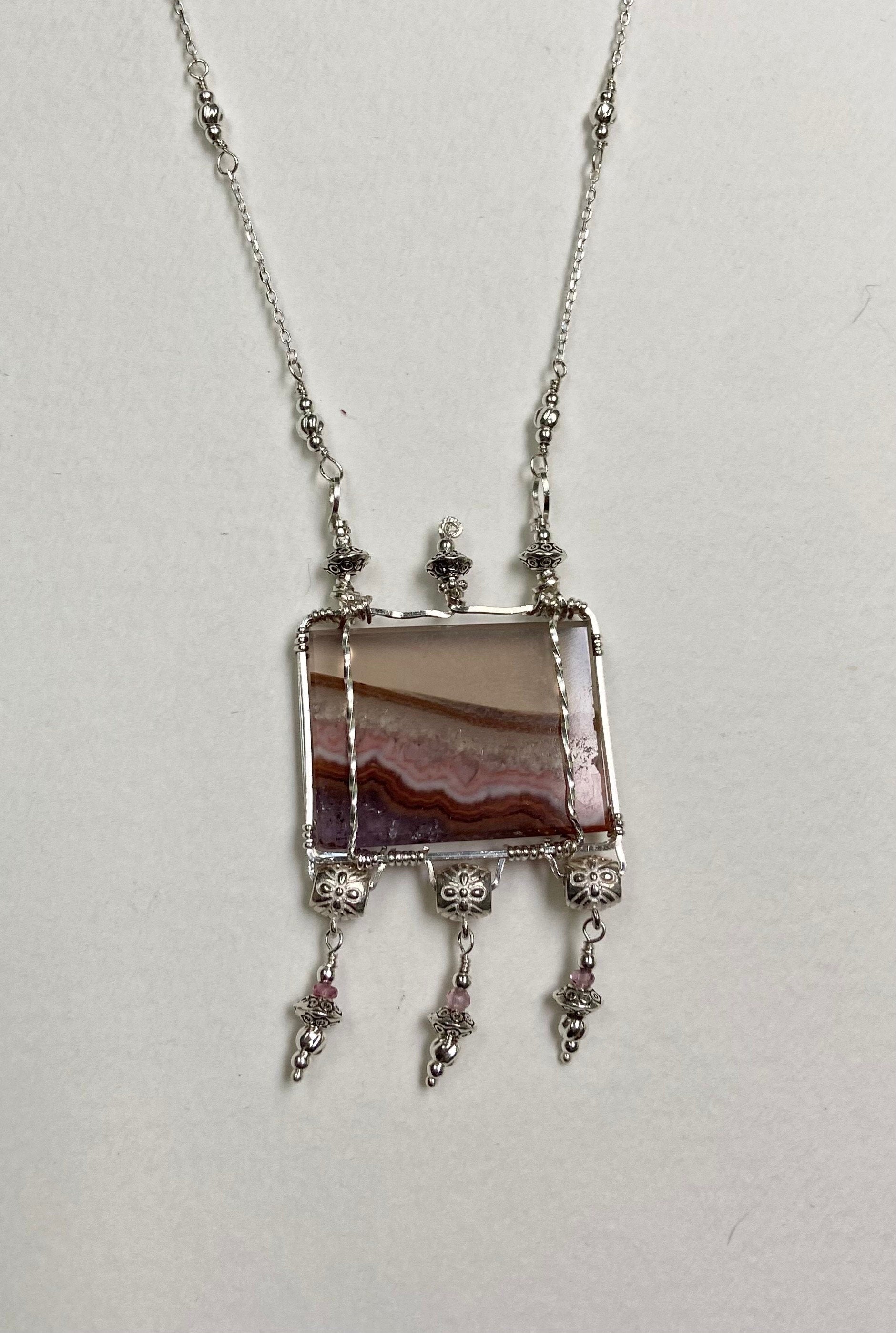 Sterling silver necklace with a rectangular agate slice pendant and pink spinel accents.