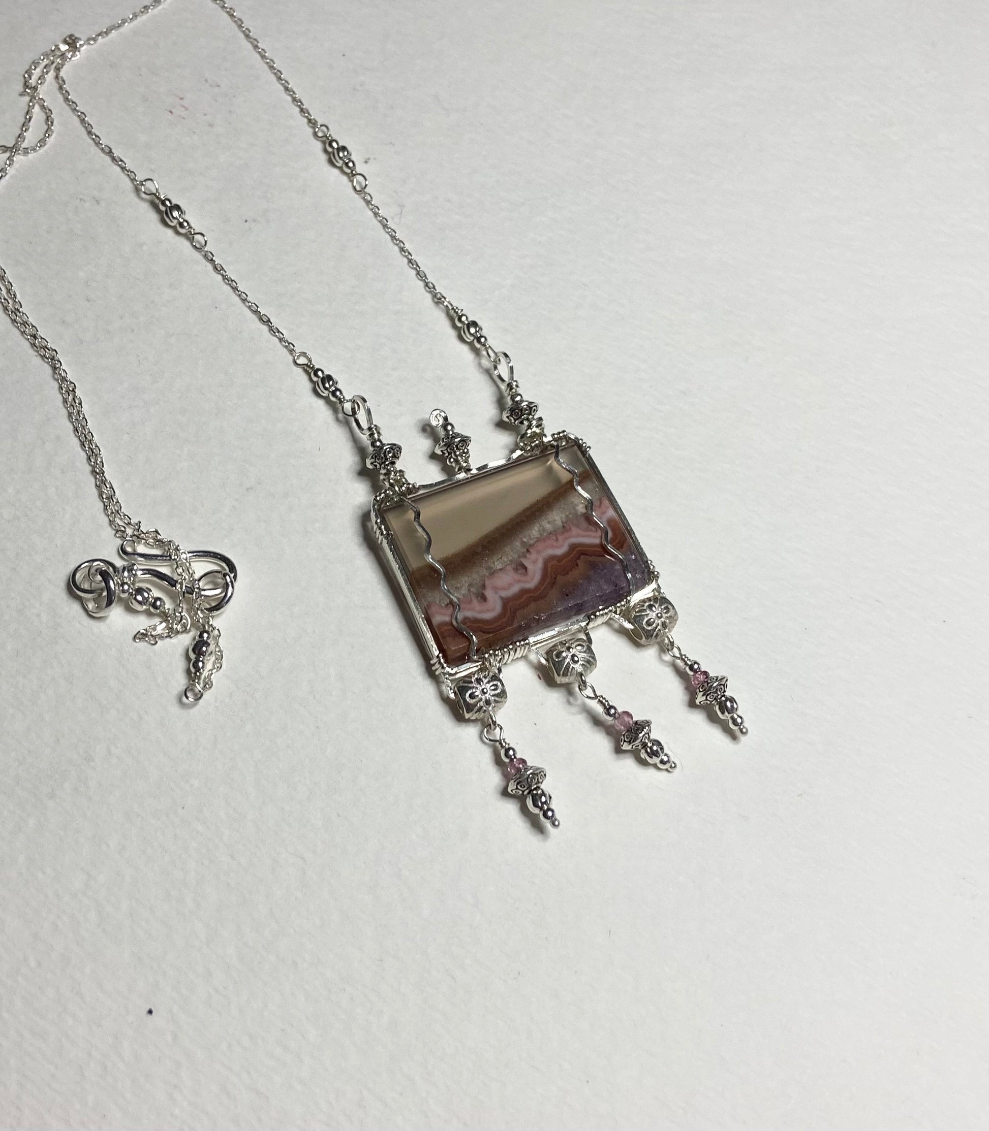 Sterling silver necklace with a rectangular agate and amethyst pendant and pink spinel accents.