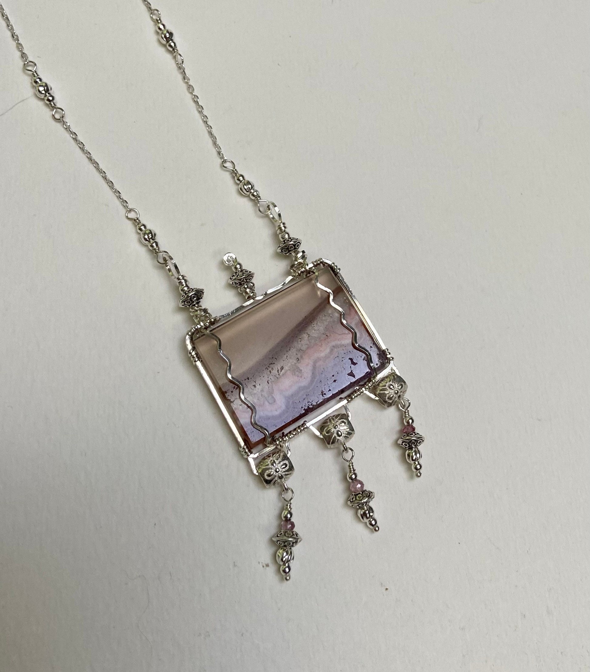 Sterling silver necklace with a rectangular agate and amethyst slice pendant and pink spinel accents.