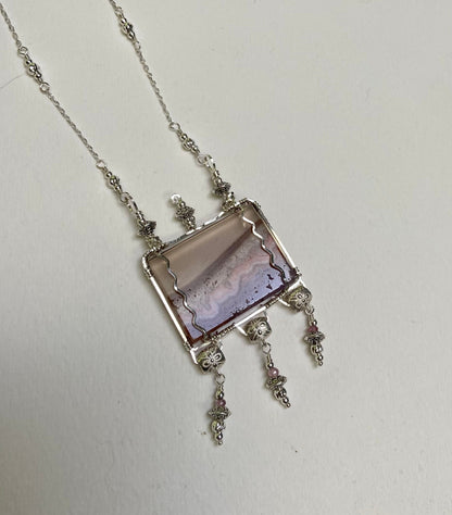 Sterling silver necklace with a rectangular agate and amethyst slice pendant and pink spinel accents.