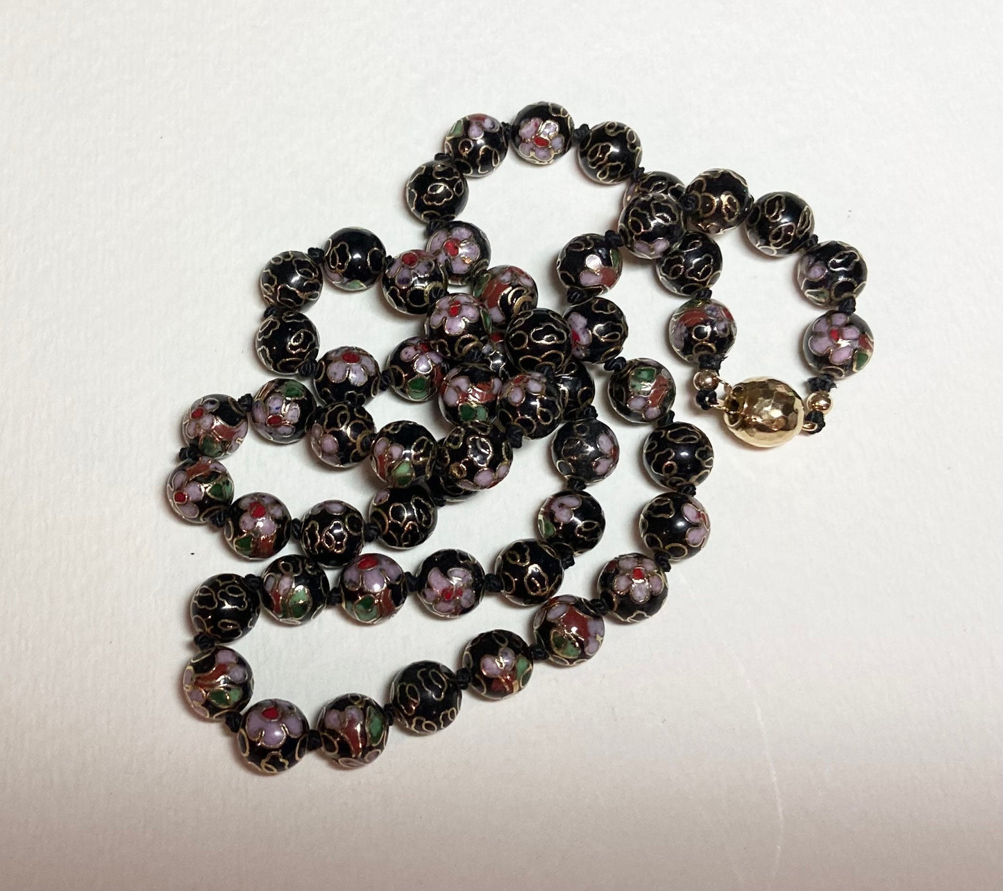 Cloisonné beaded necklace with black, pink, and gold floral designs.