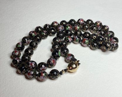 Cloisonné beaded necklace with black, pink, and gold floral designs.