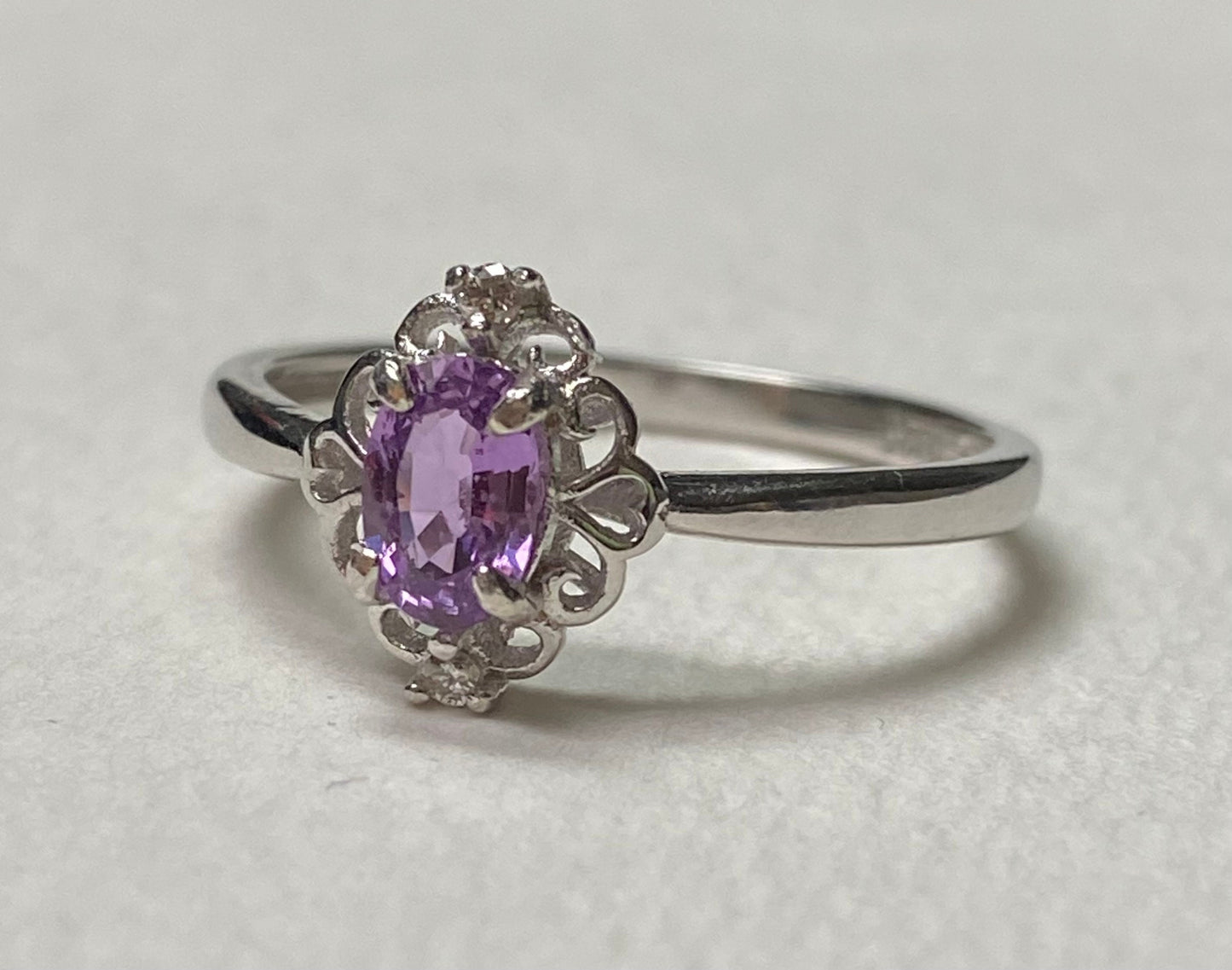 Sterling silver ring with oval pinkish-purple sapphire and diamond accents.
