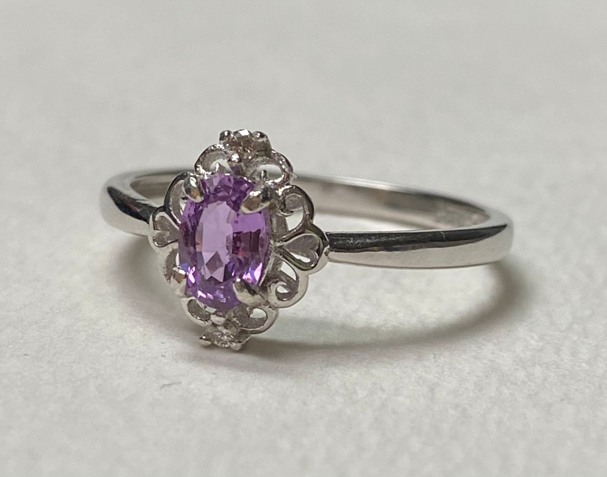 Sterling silver ring with oval pinkish-purple sapphire and diamond accents.
